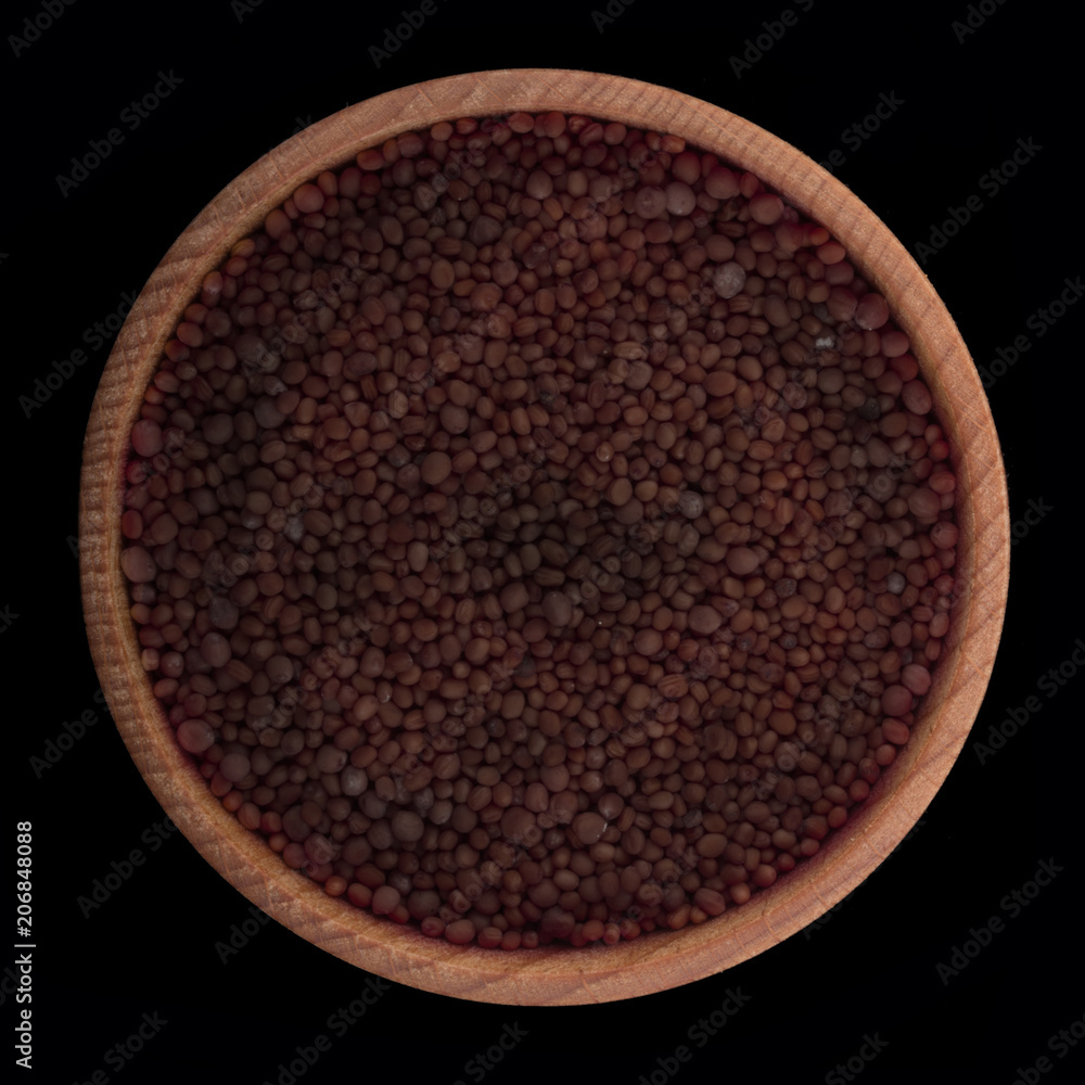 seeds of black mustrand in wooden cup isolated on black. top view seeds of black mustrand in wooden cup isolated on black. top view
