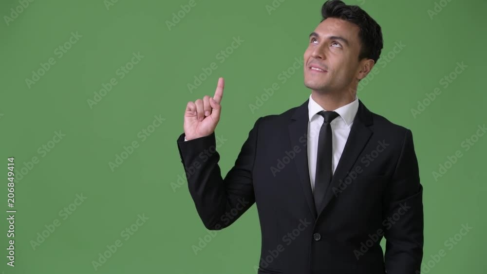 Young handsome Hispanic businessman against green background Young handsome Hispanic businessman against green background
