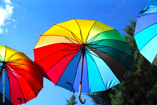 Hanging rainbow umbrellas on blue sky background