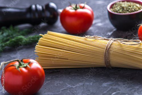 Uncooked pasta spaghetti with ingredients for tomato sauce. Concept of the composition of food design.