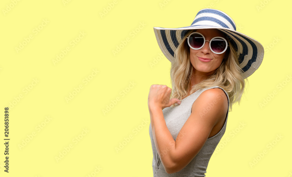Young woman wearing sunglasses and summer hat proud, excited and arrogant, pointing with victory face