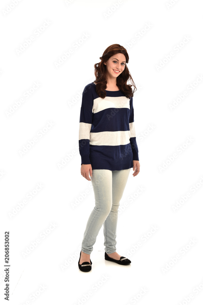  full length portrait of girl wearing striped blue and white jumper and jeans. standing pose on white studio background