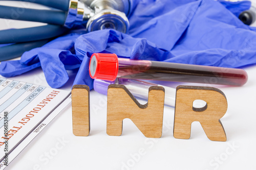 INR Clinical laboratory medical acronym or abbreviation of prothrombin time, blood test for clotting time. Word INR are near laboratory test tubes with blood sample, stethoscope and hematology result photo