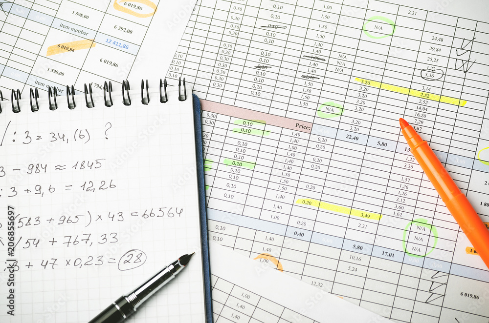 Financial tables on paper and notebook with calculations, pen and highlighter Financial tables on paper and notebook with calculations, pen and highlighter