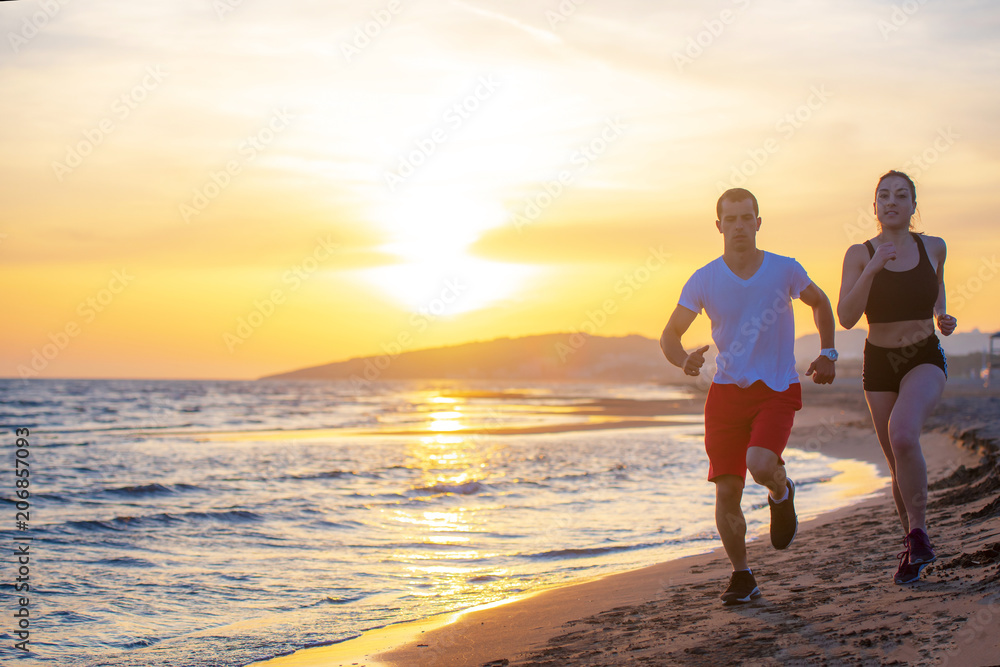 Fototapeta premium Man and women running on tropical beach at sunset