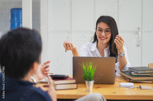 Smiling and beautiful female CEO wearing glasses talking with company subordinates, discussing business strategies. leadership concept