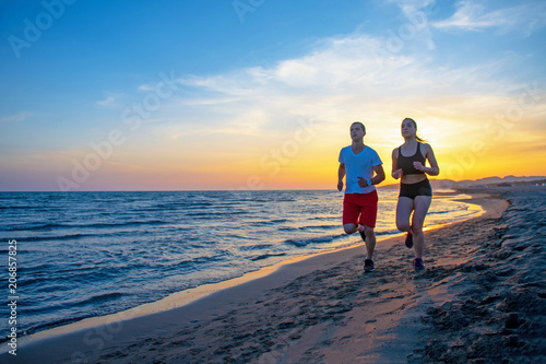 Man and women running on tropical beach at sunset