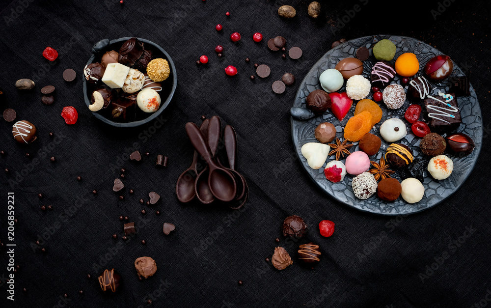 A variety of truffles in a black clay pile and chocolate spoon A variety of truffles in a black clay pile and chocolate spoon