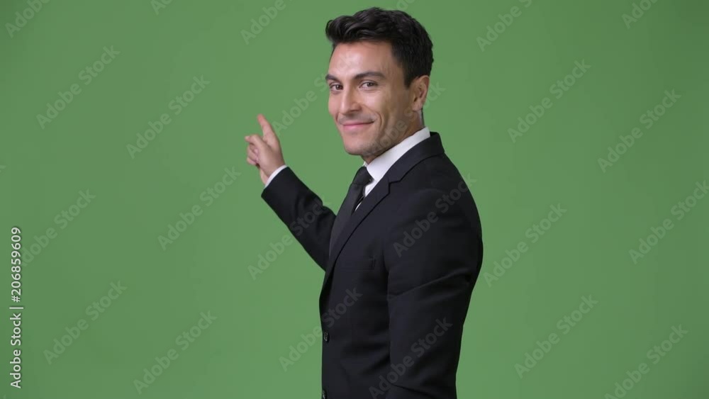 Young handsome Hispanic businessman against green background Young handsome Hispanic businessman against green background