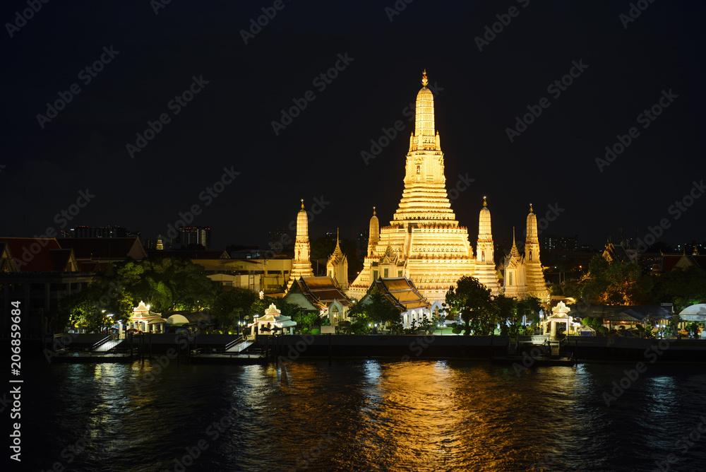 Wat Arun temple at night time with glitter light on the water