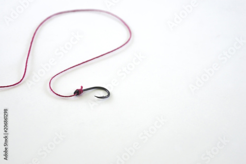A single fishing hook hooked with red rope on a white background