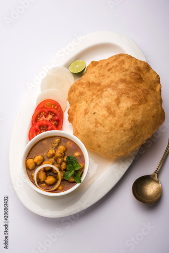 Chole Bhature or Chick pea curry and Fried  Puri served in terracotta crockery over white background. selective focus photo