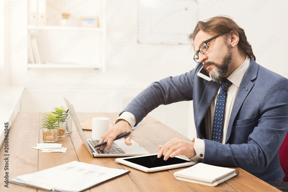 Businessman talking on phone and using tablet Businessman talking on phone and using tablet