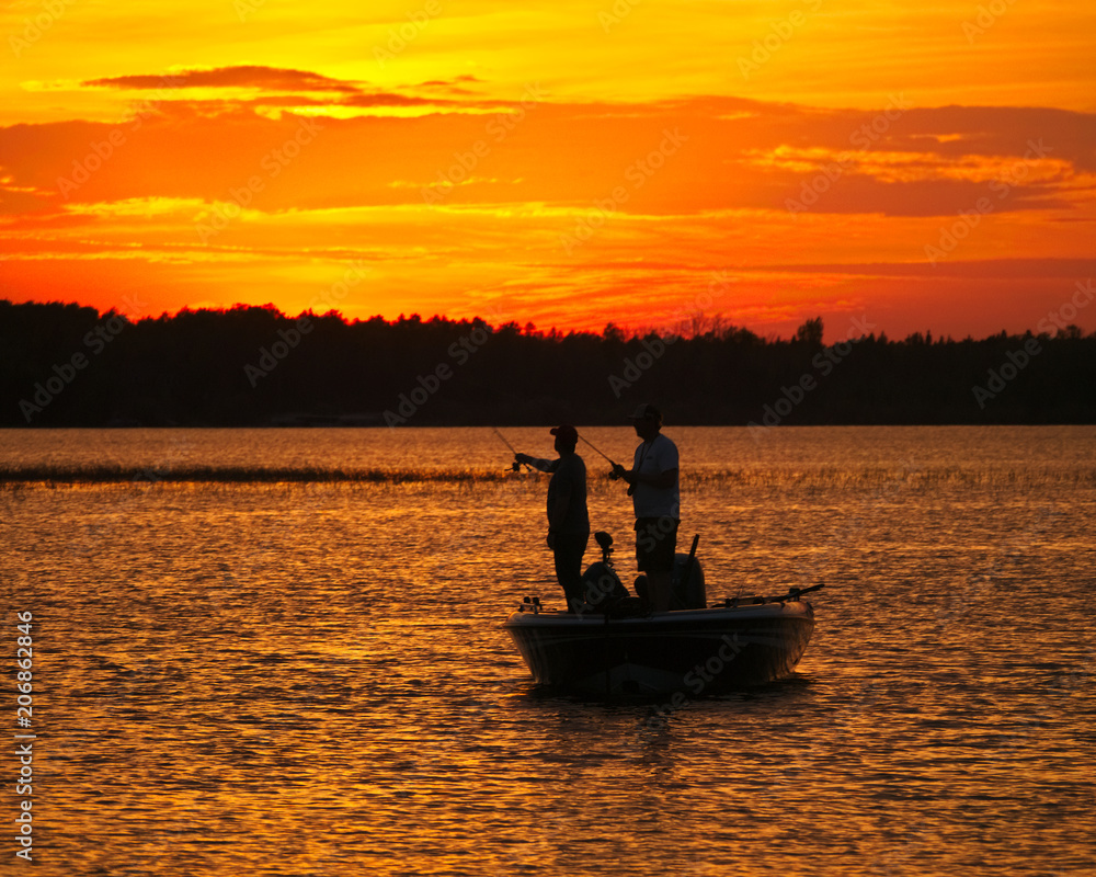 Silhouette of men fishing in a boat on a lake just after sunset in Bemidji Minnesota.