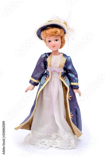 Porcelain doll in vintage white dress and a purple cape and hat