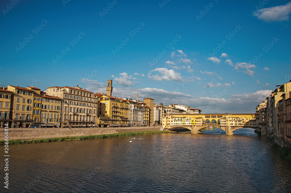 Naklejka premium Overview of the river Arno, buildings and the Ponte Vecchio (bridge) at sunset. In the city of Florence, the famous and amazing capital of the Italian Renaissance. Located in the Tuscany region