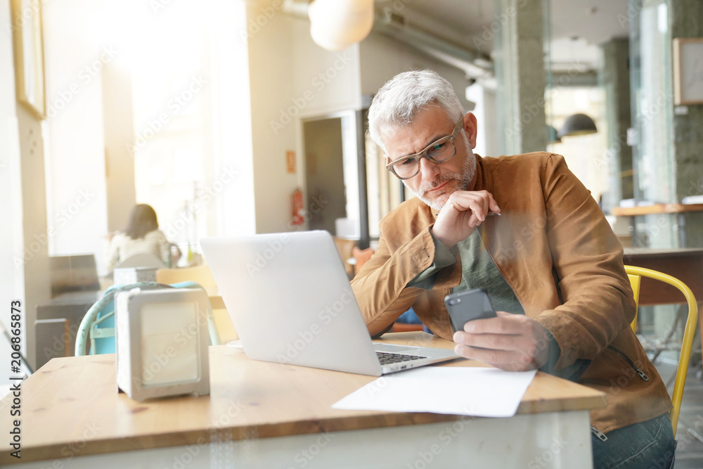 Man in trendy coffee shop working on laptop computer Man in trendy coffee shop working on laptop computer
