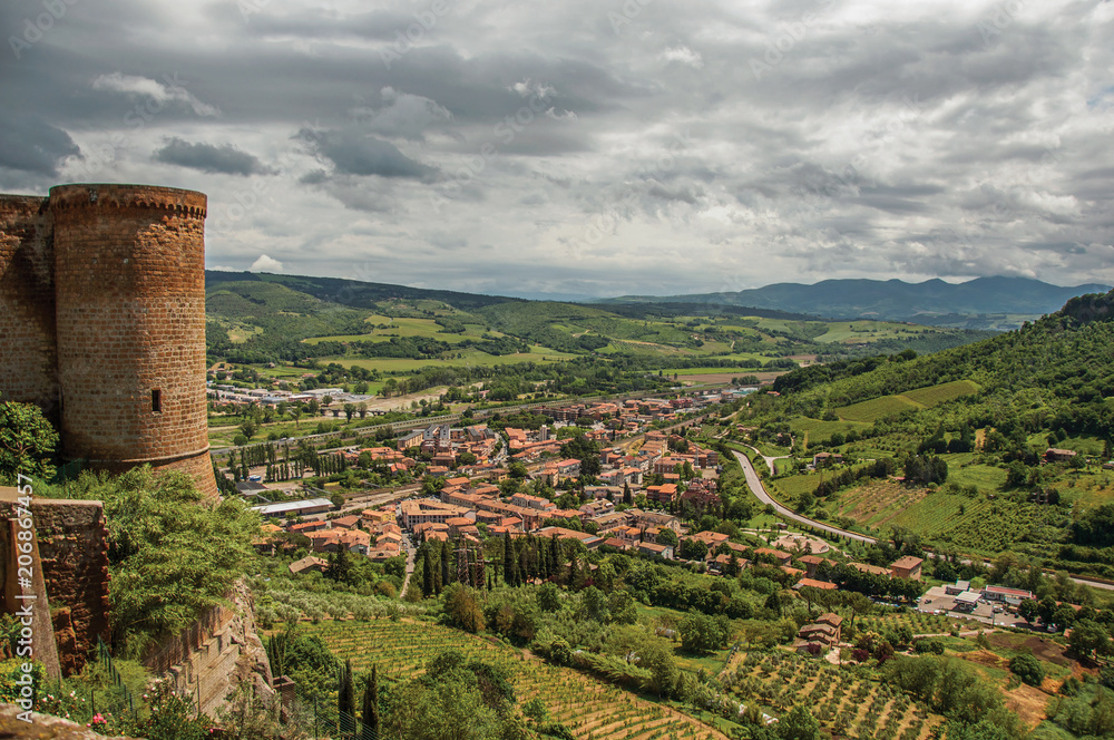 Obraz premium Overview of stone tower, green hills, vineyards and town rooftops near a road. From the city center of Orvieto, an ancient, pleasant and well preserved medieval town. Located in Umbria, central Italy