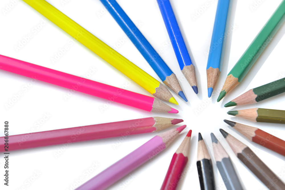 Group of coloured pencils arranged in circle on white background