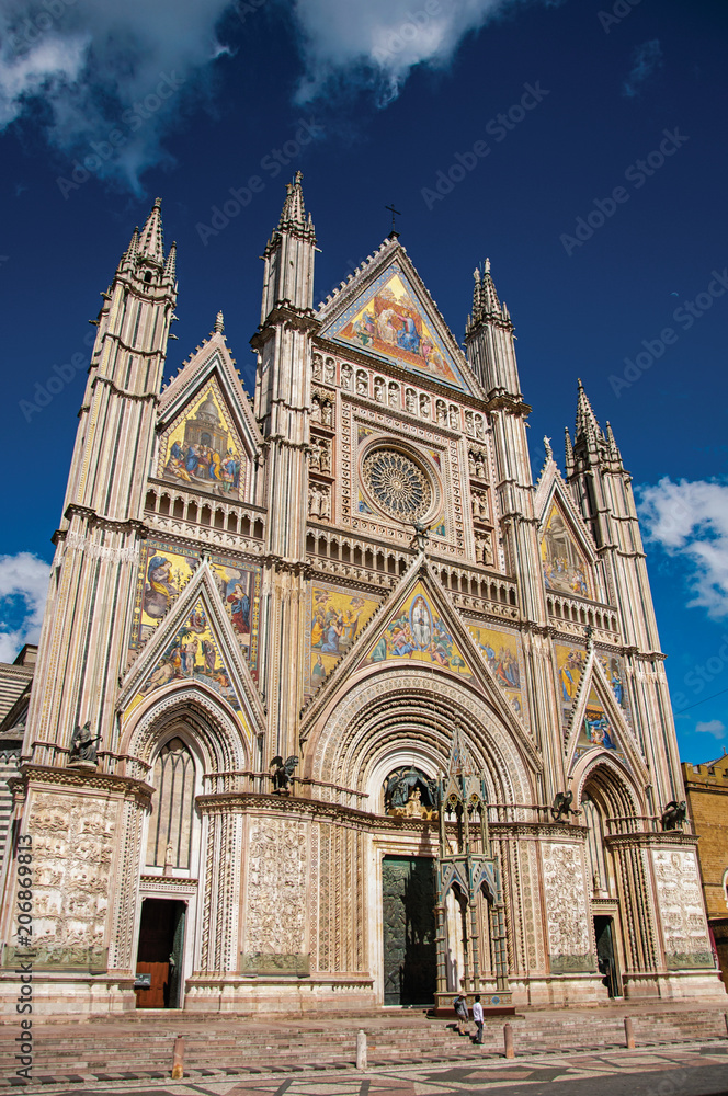 Facade view of the opulent and monumental Orvieto Cathedral (Duomo) under sunny blue sky in Orvieto, a pleasant and well preserved medieval town. Located in Umbria, central Italy