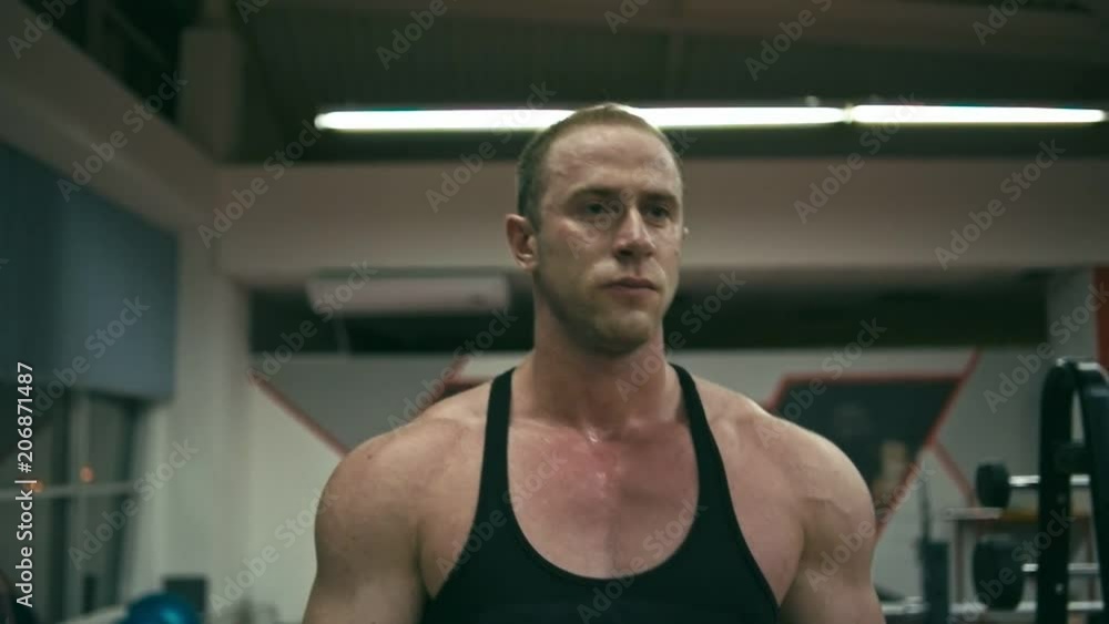 Bodybuilder walking in gym, slow motion, shallow depth of field Bodybuilder walking in gym, slow motion, shallow depth of field