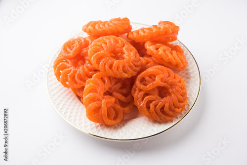 Indian sweet Imarti or Jalebi served in white ceramic plate over white background