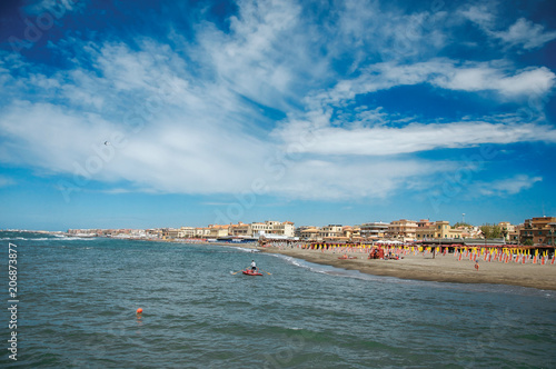 Overview of the beach and town of Ostia between the Mediterranean sea and sunny sky. The town is a seaside resort and ancient port of Rome. Located in the Lazio region