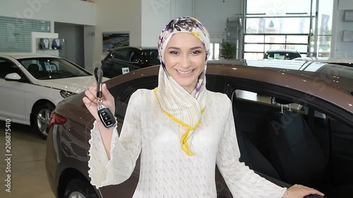 Muslim woman with car key over car show background photo