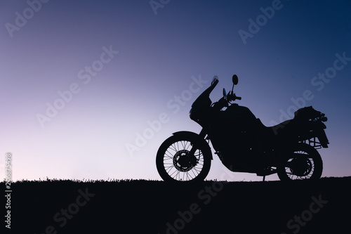 silhouette adventurous motorcycle on blue sunset sky, motorcycle touring background, adventure and travel concept, active lifestyle
