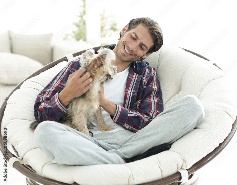 handsome guy with a dog sitting in a large armchair. handsome guy with a dog sitting in a large armchair.