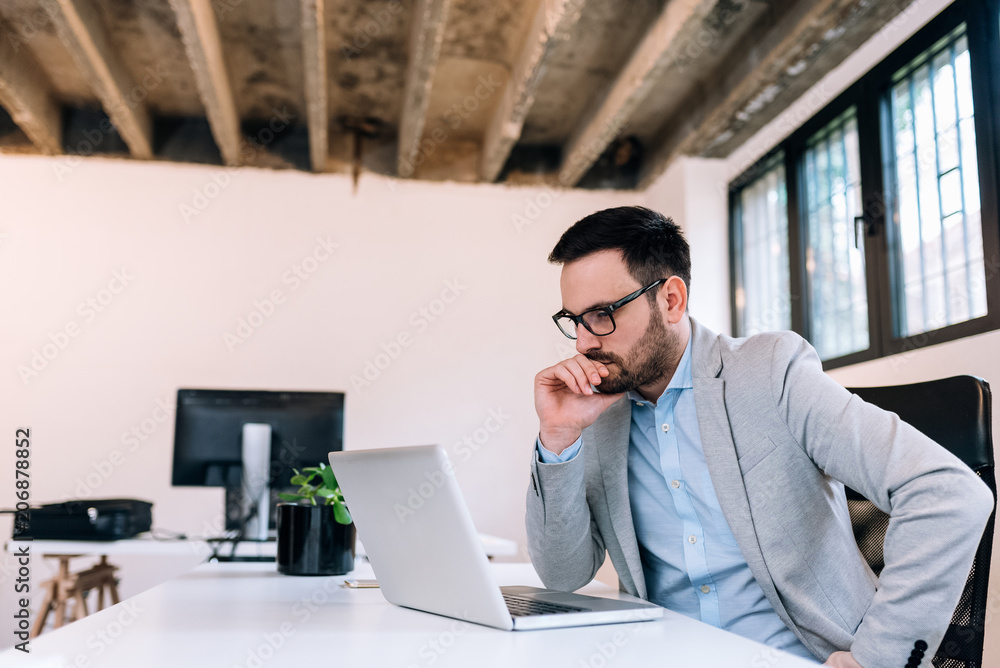 Serious businessman looking at laptop screen. Serious businessman looking at laptop screen.