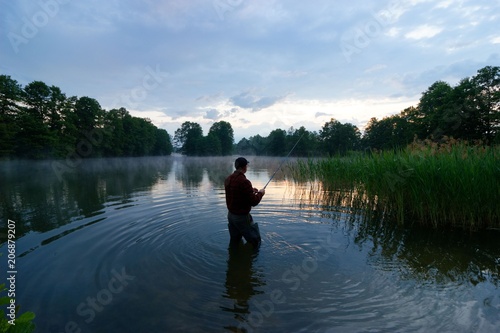 fisherman standing in the lake and catching the fish during sunrise