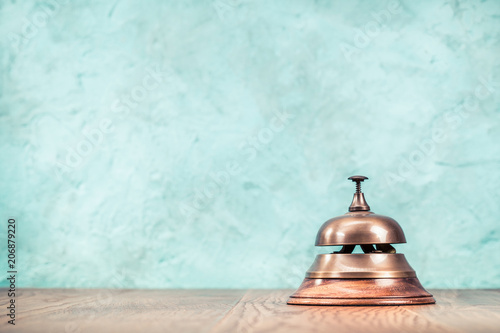 Retro hotel reception service desk bell front textured aquamarine concrete wall background. Vintage old instagram style filtered photo