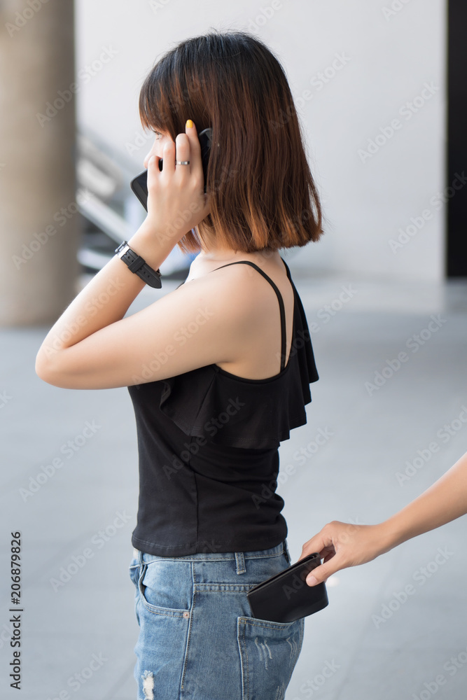 careless woman being pick pocketed; woman facing risk of urban crime of  pickpocket or pickpocketing with