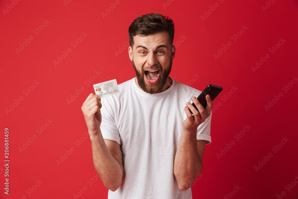 Screaming young man holding mobile phone and credit card. Looking camera. Screaming young man holding mobile phone and credit card. Looking camera.