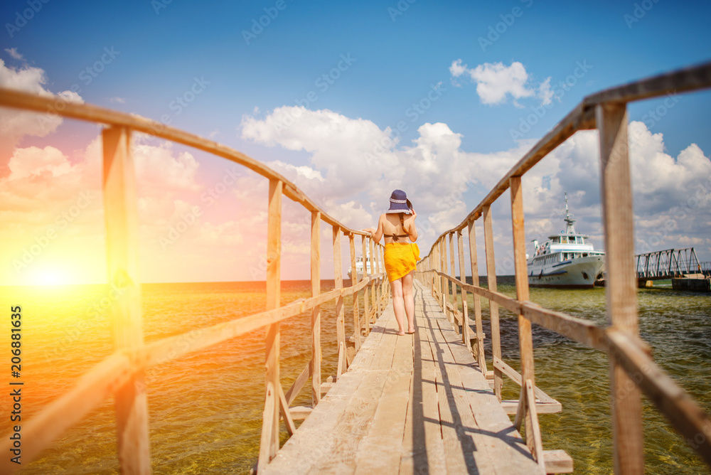 Fototapeta premium girl in a blue hat goes along the pier