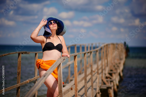 girl in a blue hat goes along the pier © cezarksv