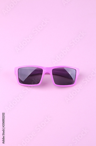 Pink sunglasses on a bright pink background. Beach accessories.