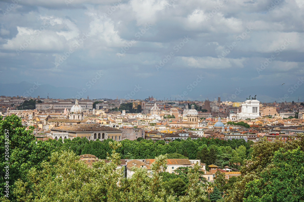 Overview of trees, cathedrals domes, monuments and roofs on a cloudy day at Rome, the incredible city of the Ancient Era, known as 