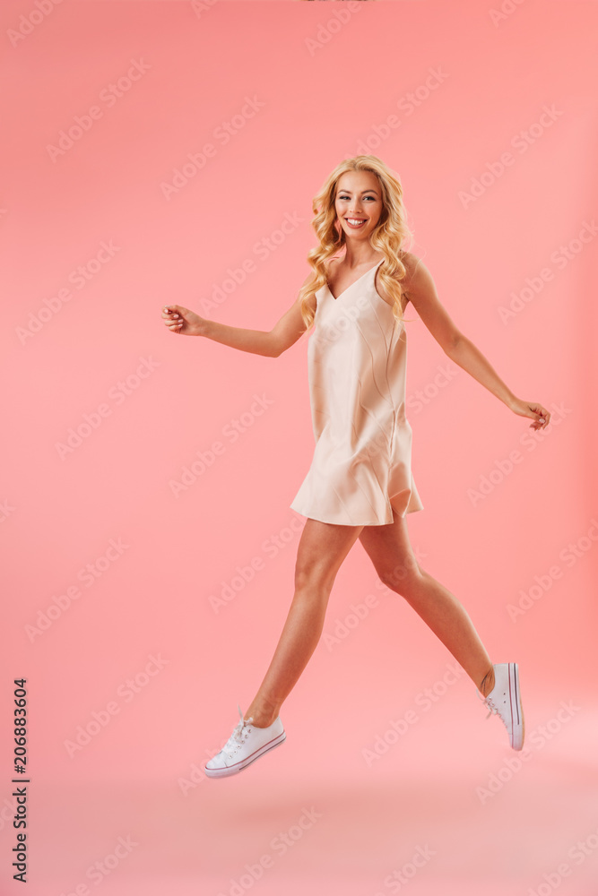Full length image of Happy blonde woman in dress running