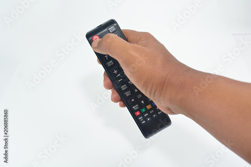 Hand is holding the TV remote to control.