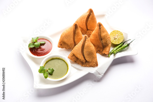 Samosa snack served with tomato ketchup and mint chutney