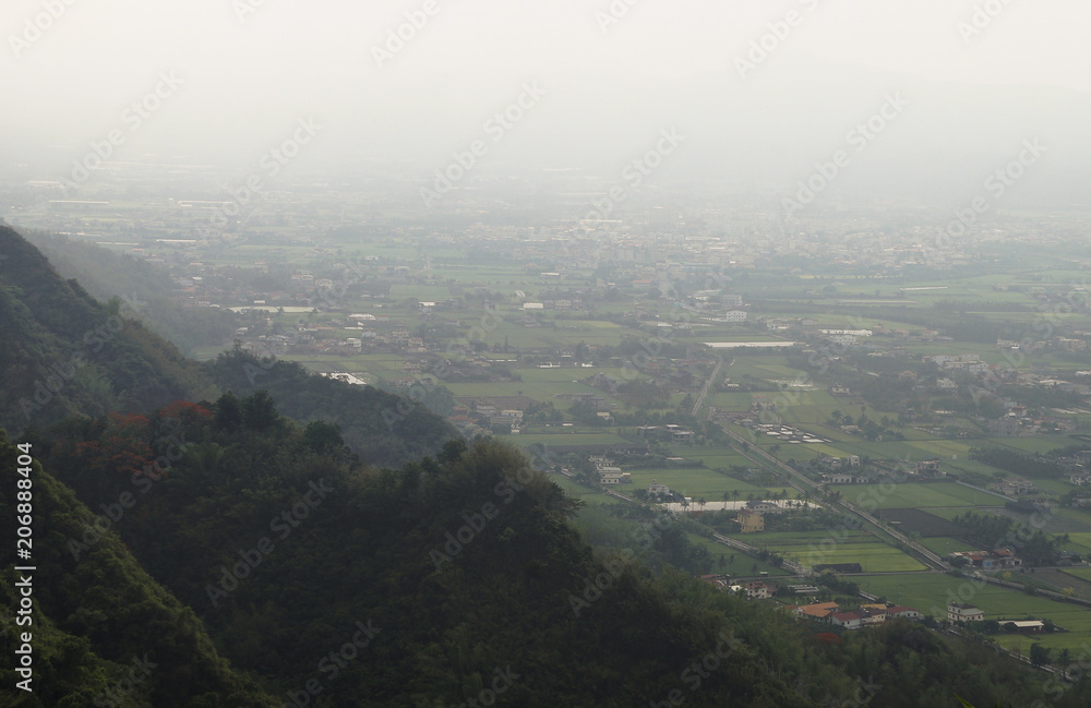 Fototapeta premium Overlooking farmland and streetscape from Qiwei Mountain in Qishan District, Kaohsiung City, Taiwan. The weather is cloudy and visibility is not good in that day.
