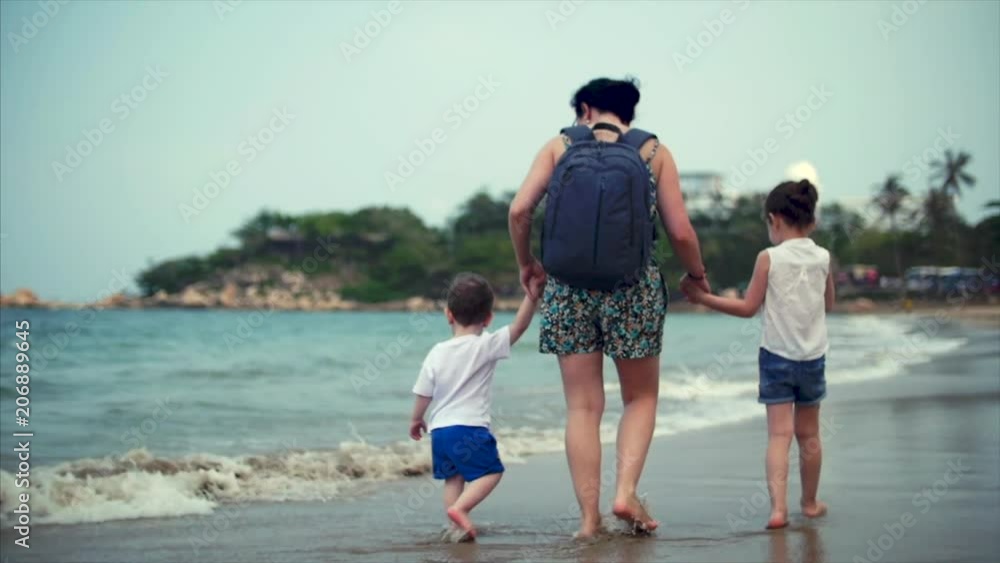 Young family, mother and children are walking along the coast. Happy family walking on sea coast. Young family, mother and children are walking along the coast. Happy family walking on sea coast.