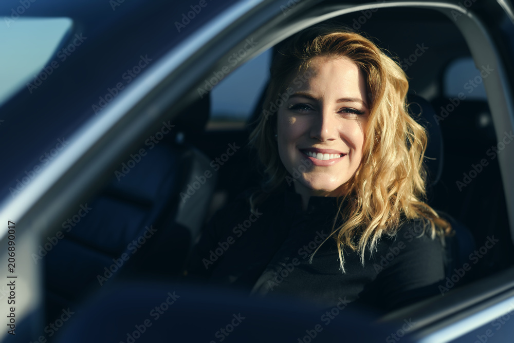 Smiling woman in the car on a summer day.