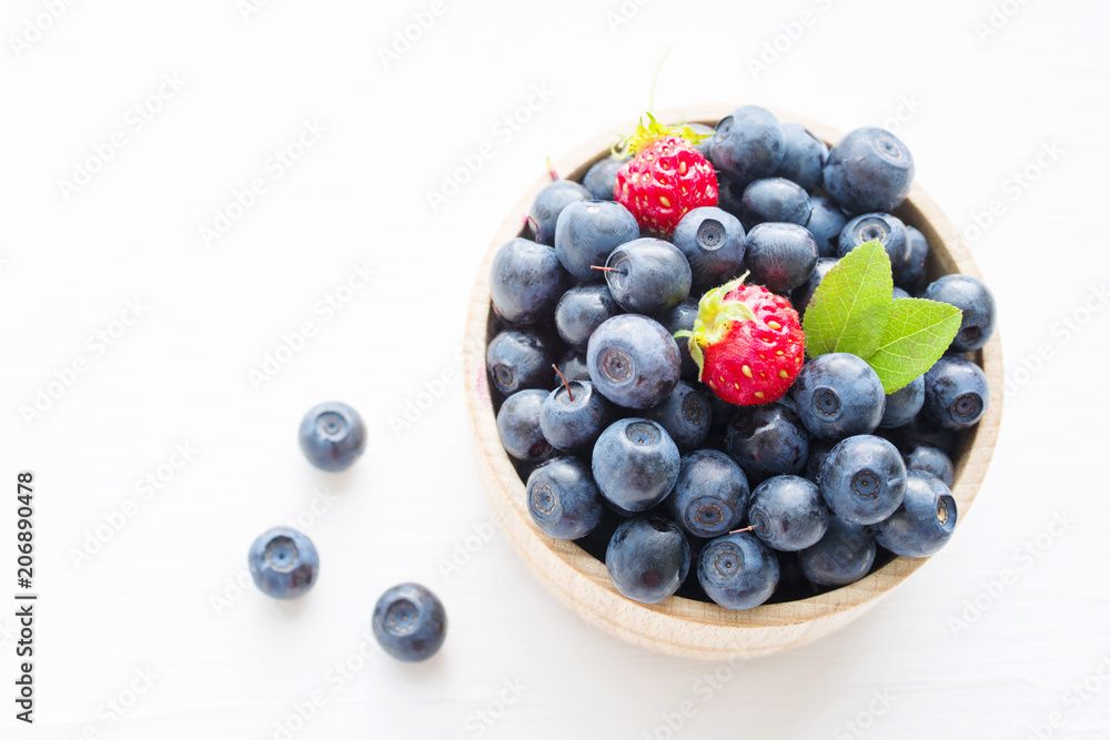 Fresh blueberries in a wooden cup on a light surface. Closeup, top view. Fresh blueberries in a wooden cup on a light surface. Closeup, top view.