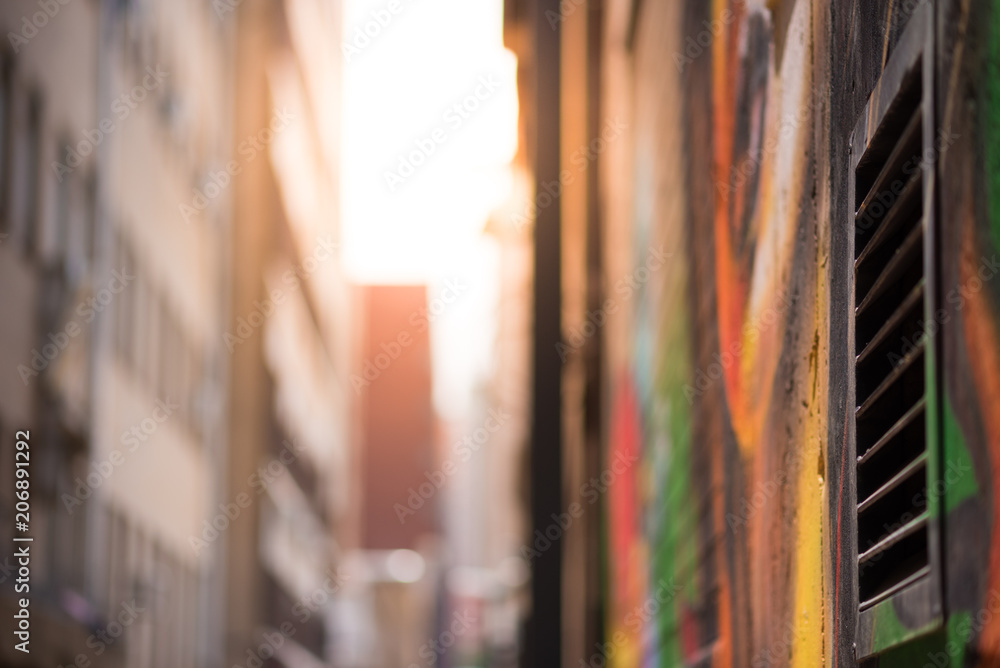 Fototapeta premium Zdjęcie abstrakcyjne stylu patrząc w dół alejki wyłożonej graffiti w kierunku słońca. Centrum Johannesburga