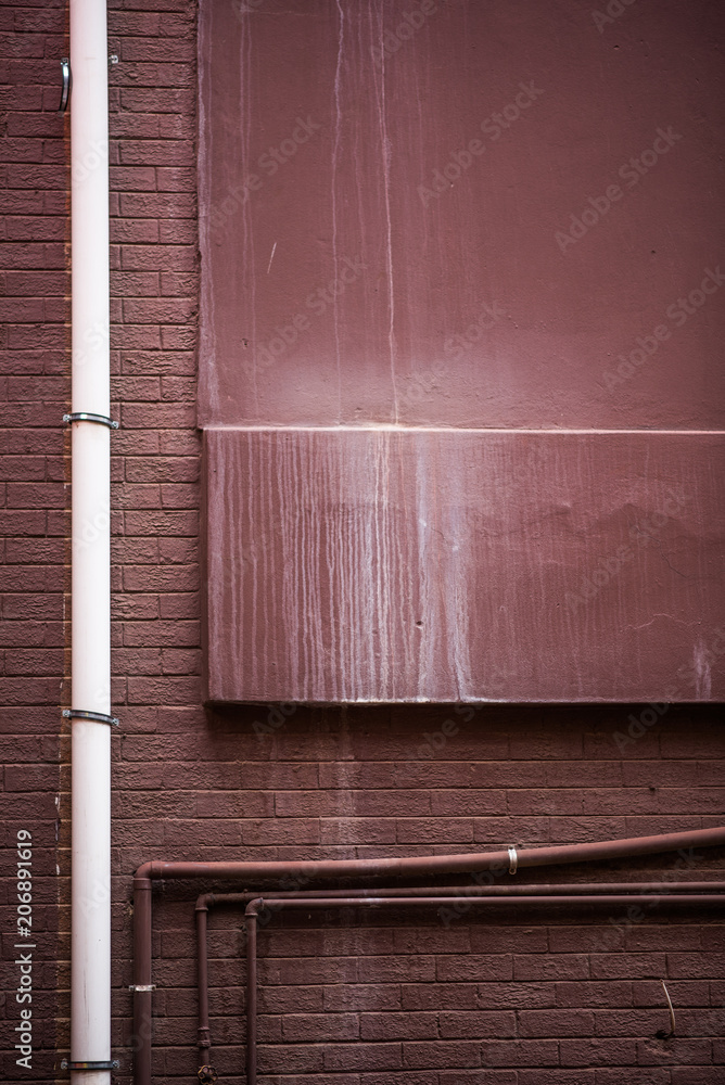 Portrait Brown painted grungy brick wall with pipes and dripping white paint
