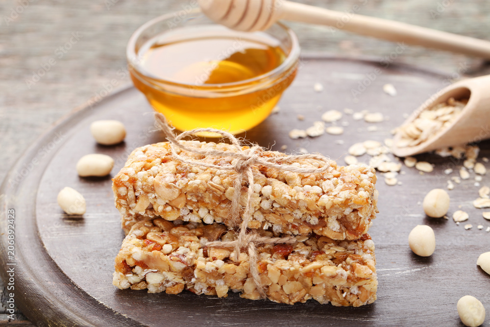 Tasty granola bars with nuts and honey in bowl on wooden table