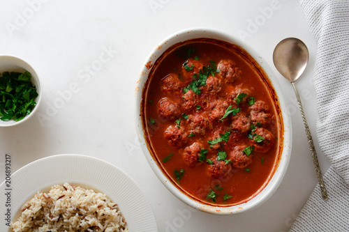 Traditional spicy meatballs in tomato sauce with garnish on a concrete background. Selective focus.